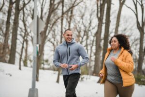 man and female running in snowy park