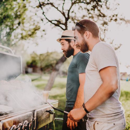 Young men cooking on barbecue, grilling meat and vegetables